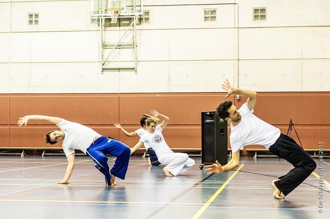 Vita leading a workshop in a sports hall, everyone dropping back into a low ponte together