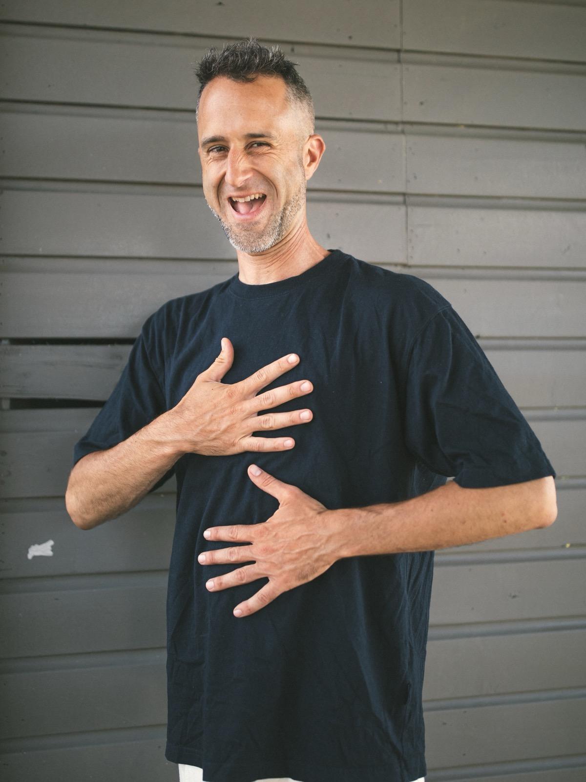 Vita laughing at the camera, both hands on his chest