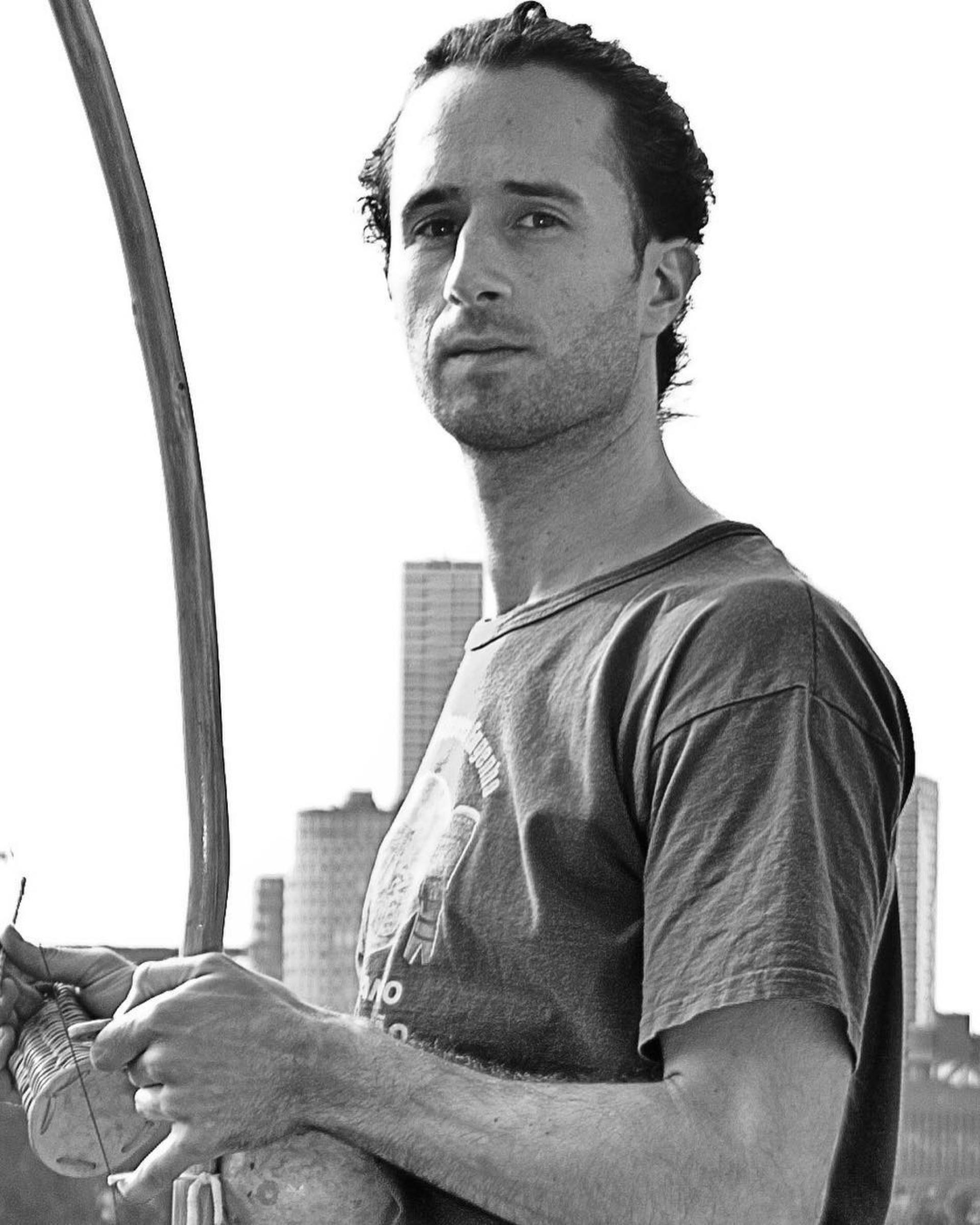 Black and white portrait with a berimbau, city skyline behind